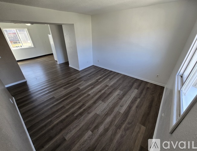 A spacious room with wooden flooring and white walls.