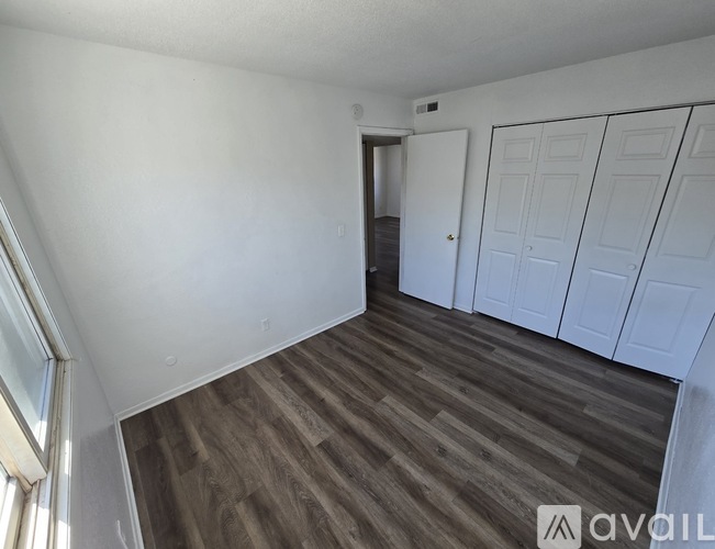 A room with a wooden floor and white walls, with a door on the right side.