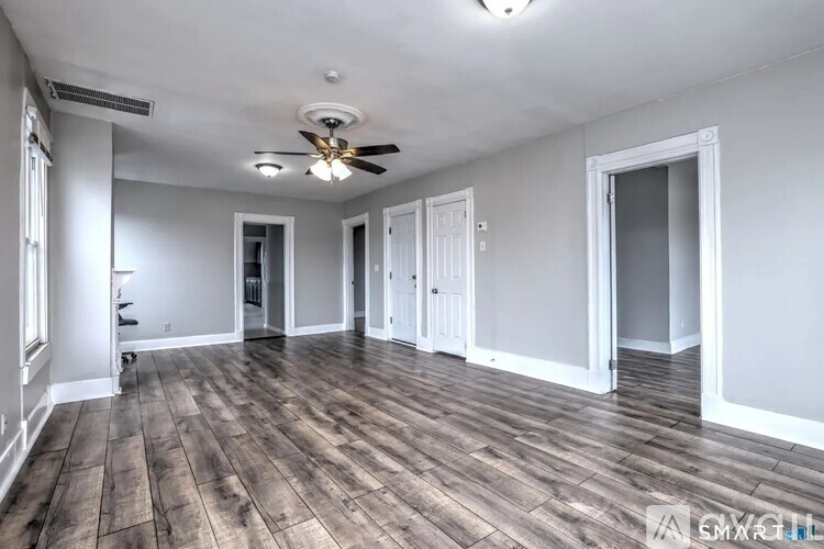 A spacious room with wood flooring and a ceiling fan.