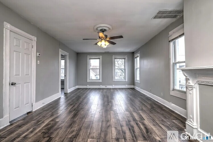 A spacious room with wood flooring and a ceiling fan.