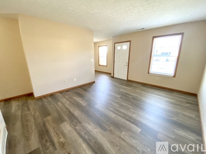 A spacious room with wooden flooring and two doors.