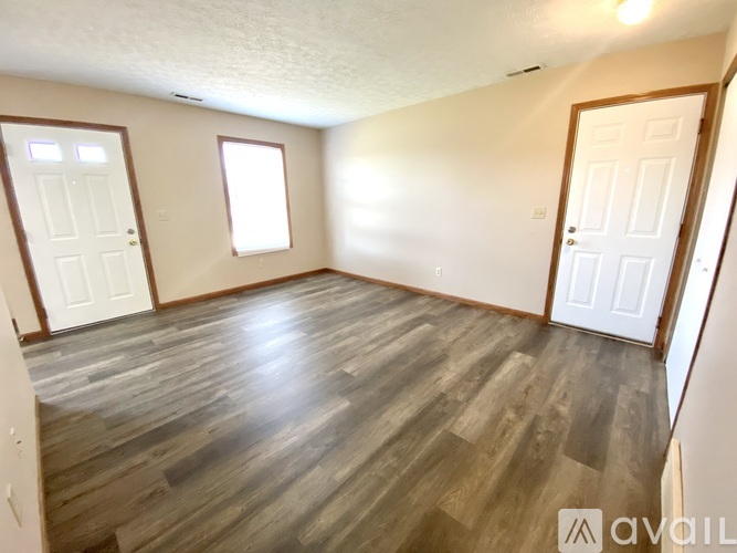 A room with wooden flooring and three doors.
