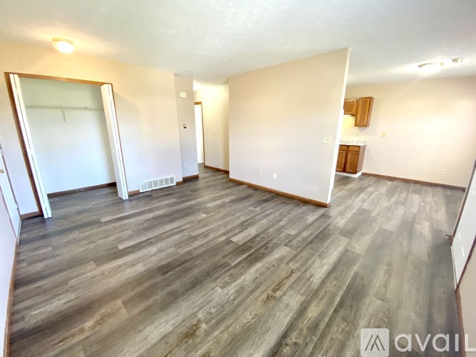 A spacious room with wooden flooring and white walls.