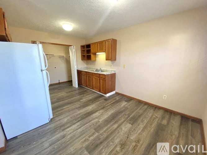 A kitchen area with a white refrigerator and wooden flooring.