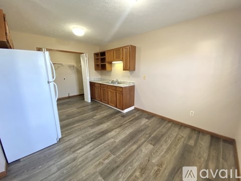 A kitchen area with a white refrigerator and wooden flooring.