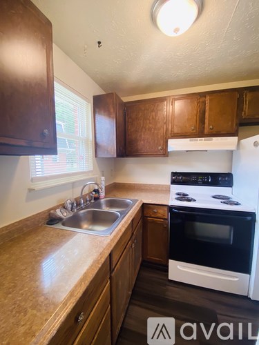 A kitchen with wooden cabinets and a white stove top oven.