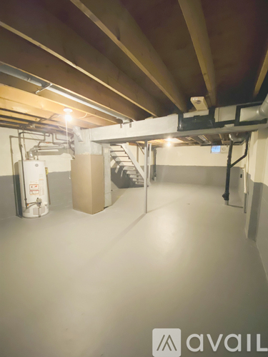 A large empty room with a staircase and a tank on the left side.