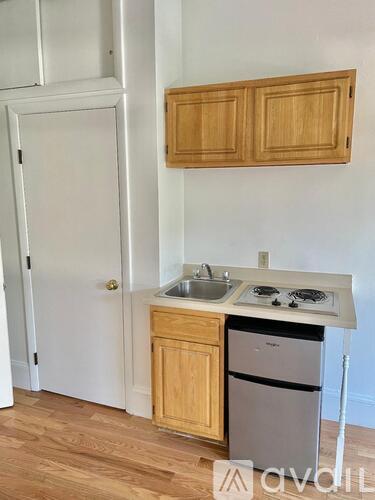 A kitchen with a white door, wooden cabinets, and a white countertop.