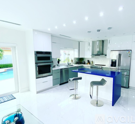 A modern kitchen with a blue bar stool.
