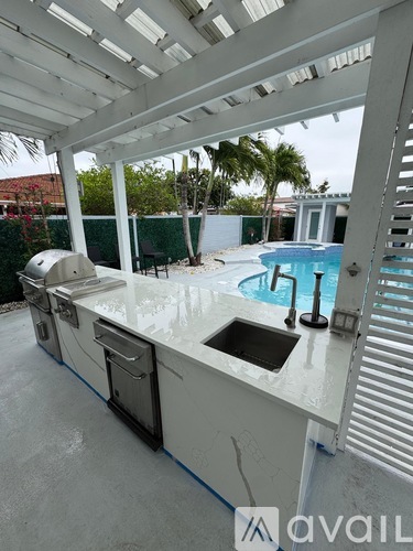 A white outdoor kitchen with a sink and grill.