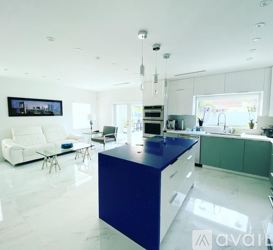 A modern kitchen with a blue island and white furniture.