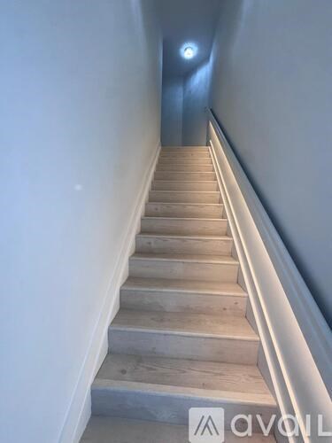 A staircase with wooden steps and a light on the wall.