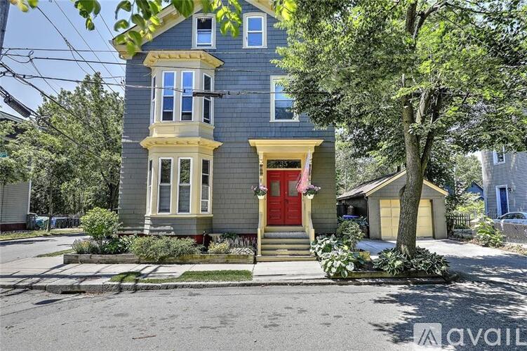 A blue house with a red door and a tree in front.
