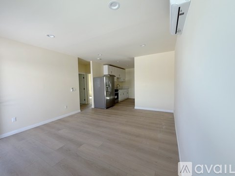 A spacious room with a kitchen area in the background.