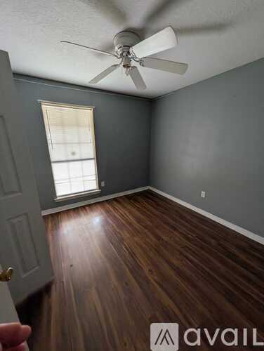 A room with a ceiling fan and wooden flooring.
