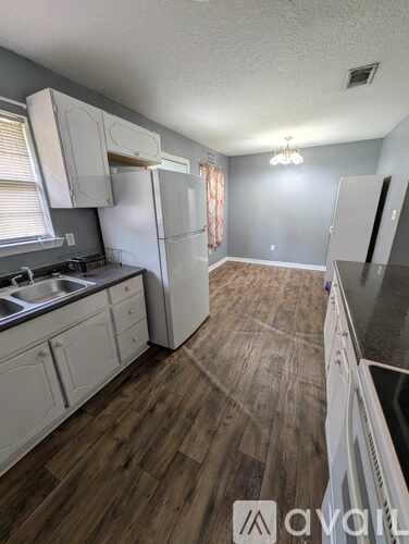 A kitchen with white cabinets and a wooden floor.
