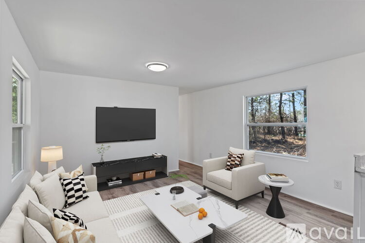 A living room with a white couch, a coffee table, and a flat screen TV mounted on the wall.