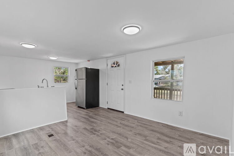 A spacious kitchen with a black refrigerator and wooden flooring.