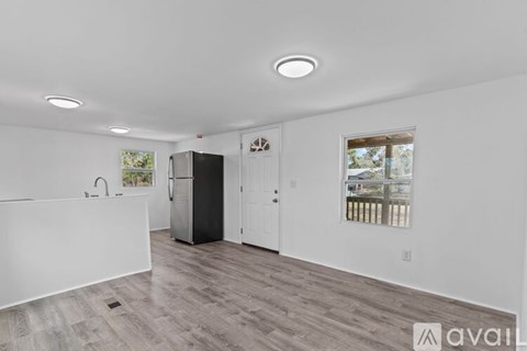 A spacious kitchen with a black refrigerator and wooden flooring.