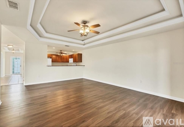 A spacious room with wooden flooring and a ceiling fan.