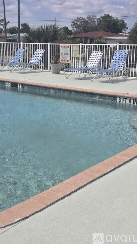 A pool with blue chairs and a sign on a fence.