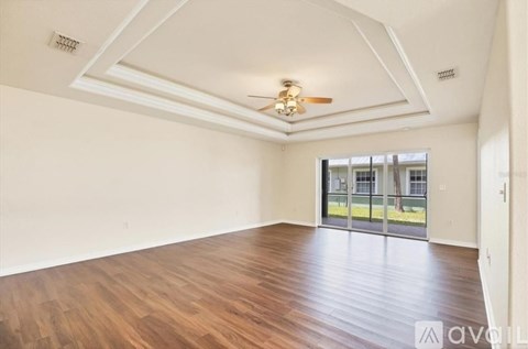 A spacious room with wooden floors and a ceiling fan.