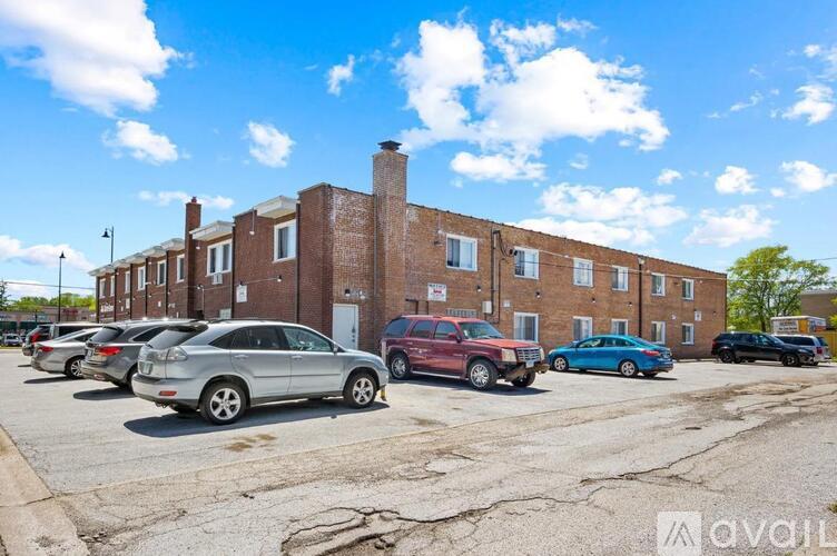 A parking lot with cars and a brick building in the background.