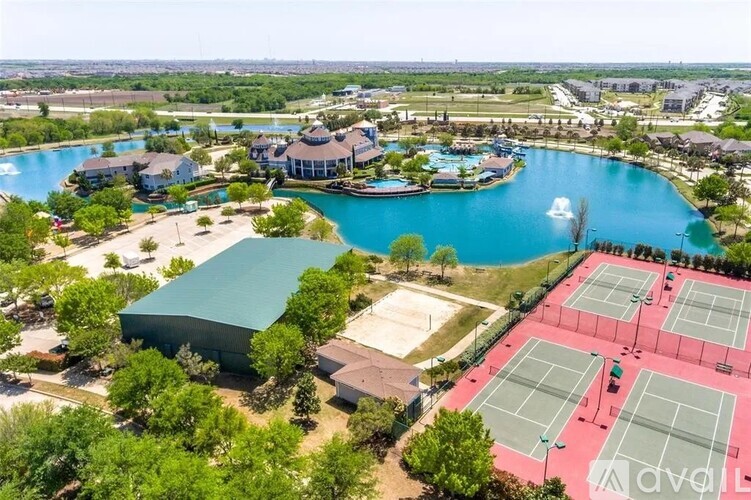 An aerial view of a tennis court surrounded by a pool and buildings.