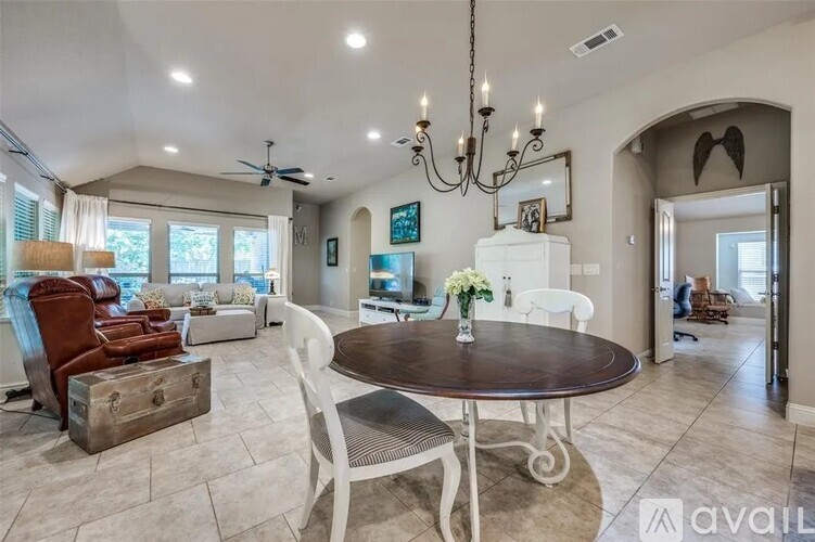 A living room with a brown table and white chairs.