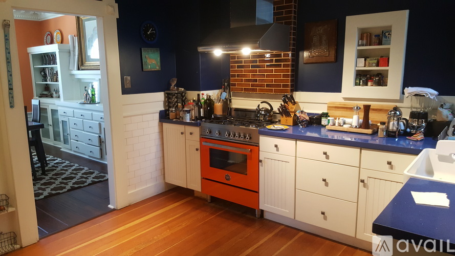 A kitchen with a white counter and orange oven.