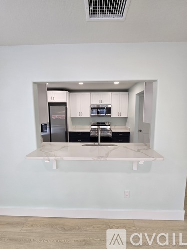 A kitchen with white cabinets and a marble countertop.