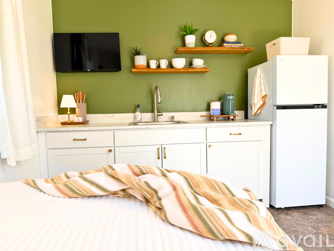 A bedroom with a bed, a green wall, and a white refrigerator.