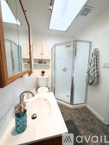 A bathroom with a sink, mirror, toilet and shower.
