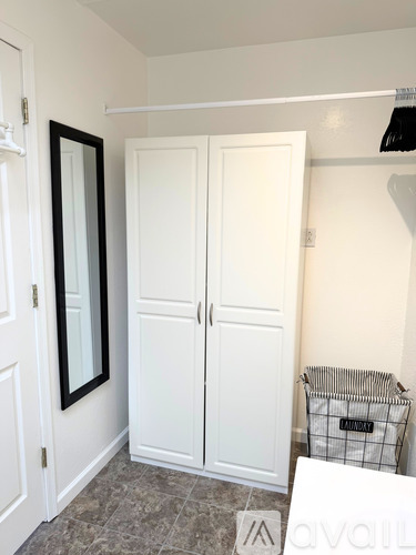 A white double wardrobe with a mirror above it and a laundry basket on the floor.