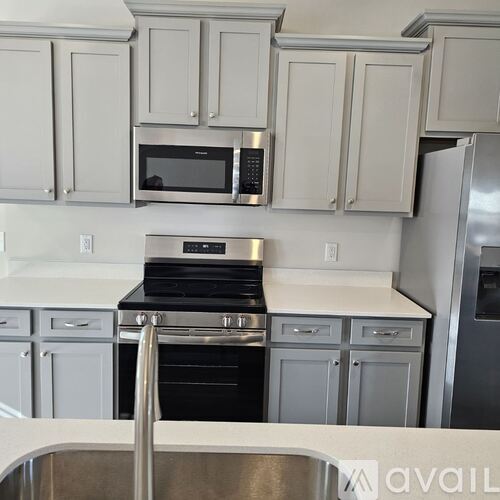 A kitchen with a stove, microwave, and refrigerator.