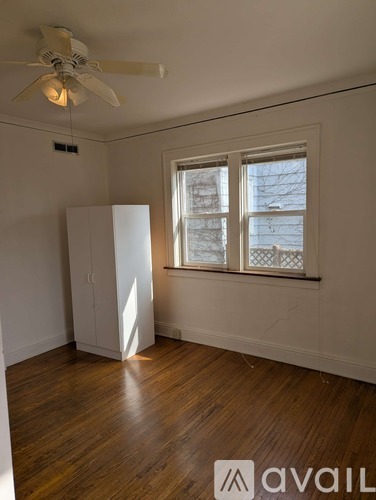 A room with a ceiling fan and a window with a view of a building outside.