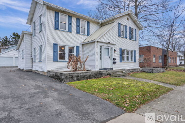 A white house with blue shutters is for sale.