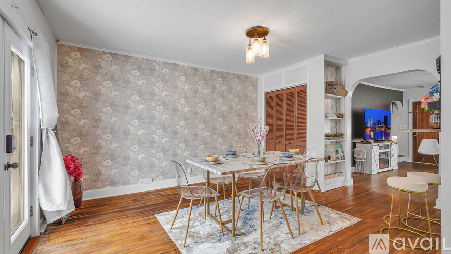 A dining room with a table set for four and a chandelier hanging from the ceiling.