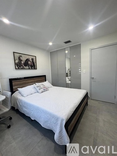 A bedroom with a bed, a chair, and a painting on the wall.