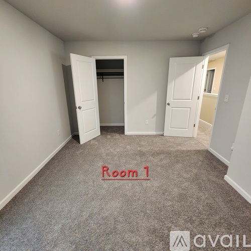 A room with carpeted floor and a doorway leading to another room.