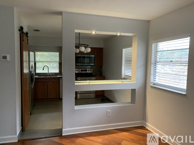 A kitchen with a refrigerator, sink, and stove is visible through a window.