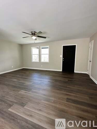 A room with a ceiling fan and wooden flooring.