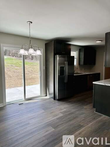 A kitchen with a black fridge and a wooden floor.