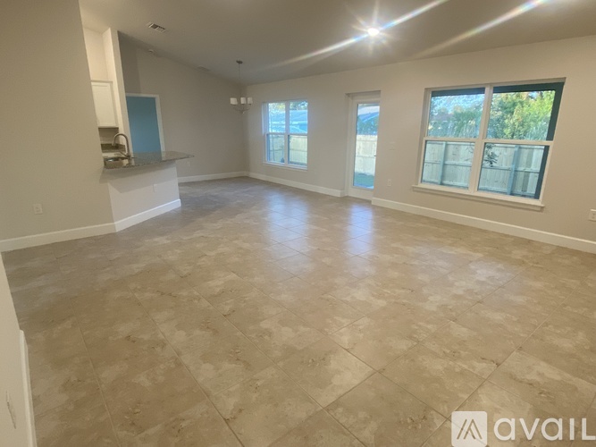 A spacious room with tiled flooring and large windows.