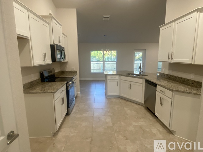 A kitchen with white cabinets and a granite countertop.