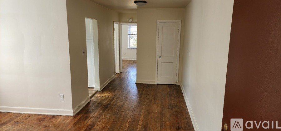 A long hallway with wood floors and white walls.