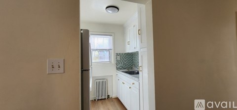 A kitchen with a refrigerator, sink, and cabinets.