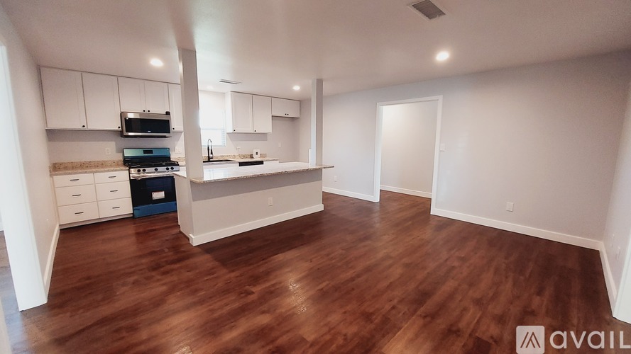 A kitchen with white cabinets and a wooden floor.