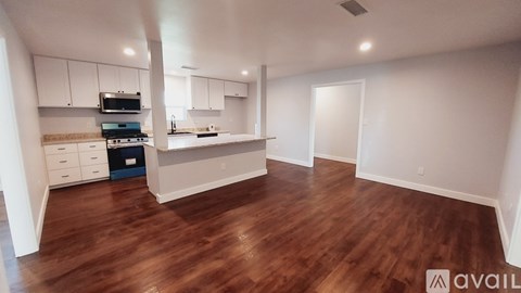 A kitchen with white cabinets and a wooden floor.