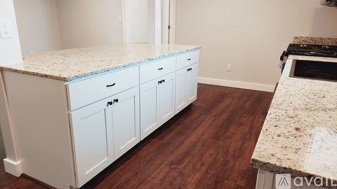 A kitchen with white cabinets and a granite countertop.